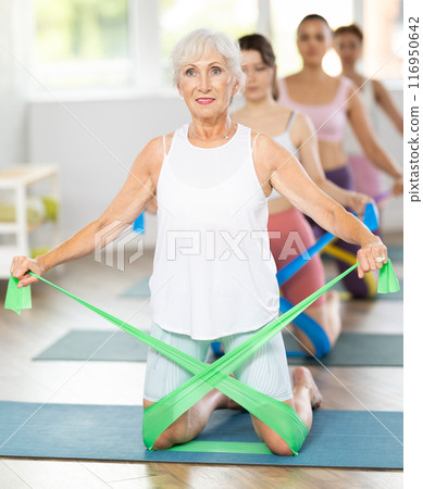 Women are doing stretching exercise with resistance bands in gym. Teamwork, good mood and healthy lifestyle concept 116950642