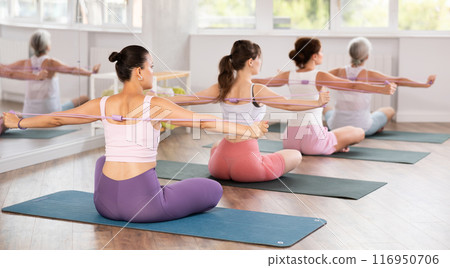 Group of women exercising with pilates loop back view 116950706