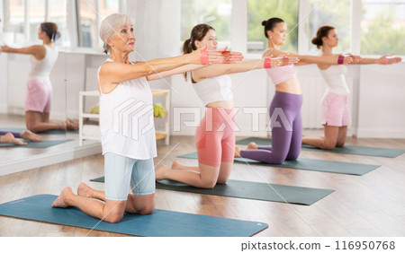 Senior lady exercising with resistance loop band during pilates class Senior lady exercising with resistance loop band during pilates class 116950768