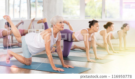 Senior lady doing xercises with figure eight resistance band in studio 116950778