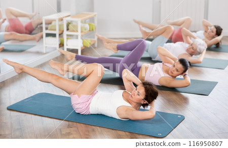 Woman doing elbow to knee crunches during group pilates training 116950807