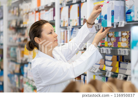 Woman seller puts medical cosmetics and other body care products on shelves 116950837