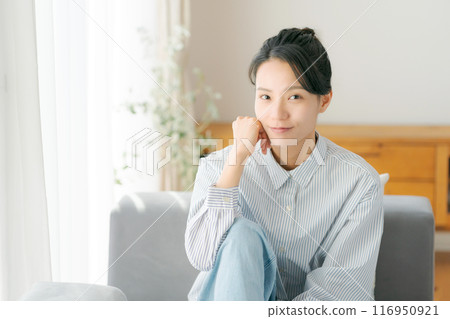 A woman in her 30s relaxing in the living room A woman in her 30s relaxing in the living room 116950921