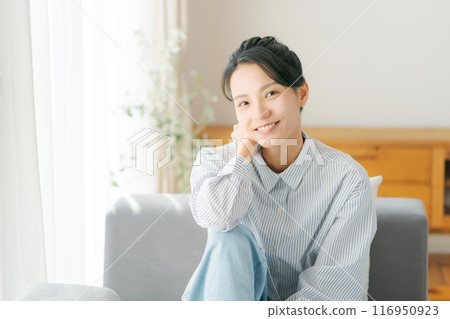 一位 30 多歲的女性在客廳放鬆 一位 30 多歲的女性在客廳放鬆 116950923