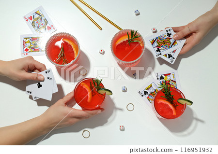 Grapefruit cocktails, cards in hands and rings on white background, top view Grapefruit cocktails, cards in hands and rings on white background, top view 116951932