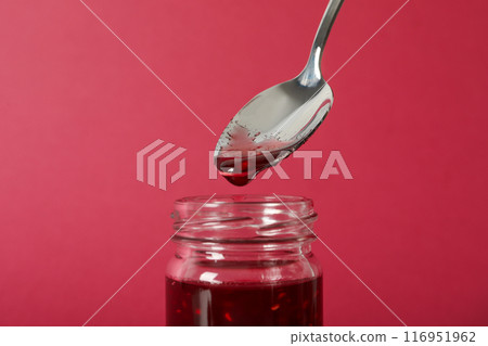 Jar with fig jam and spoon on pink background, close up 116951962
