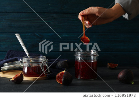 Figs, jar of jam and spoon in hand on blue wooden background Figs, jar of jam and spoon in hand on blue wooden background 116951978