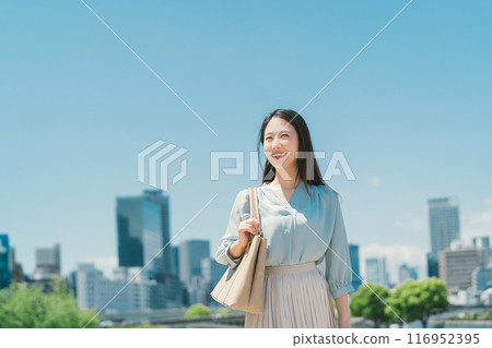 Business woman against the backdrop of the blue sky and buildings Business woman against the backdrop of the blue sky and buildings 116952395