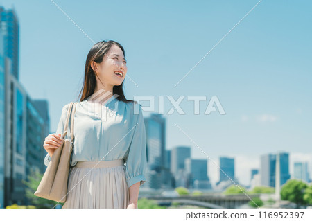 Business woman against the backdrop of the blue sky and buildings Business woman against the backdrop of the blue sky and buildings 116952397
