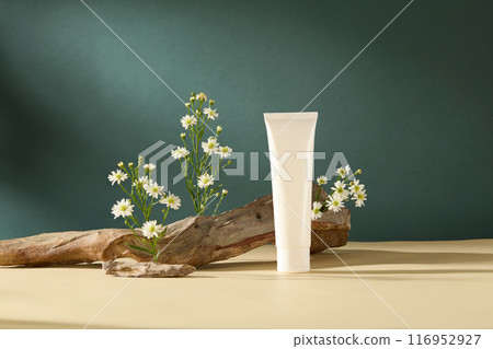Minimalist style photography with natural concept, white vegan cosmetic tube displayed on the table with rock, log and flowers decorated around. Blank space for promotional and adding text 116952927