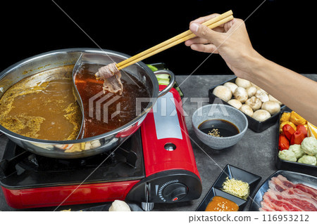 A hand holding chopsticks with a piece of meat on it A hand holding chopsticks with a piece of meat on it 116953212