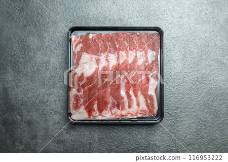 A tray of meat is on a grey surface 116953222