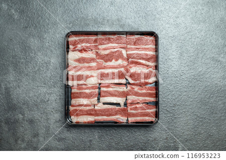 A tray of meat is on a grey surface 116953223