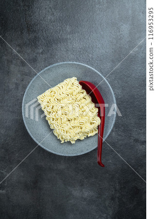 A bowl of instant noodles with a red spoon on top A bowl of instant noodles with a red spoon on top 116953295