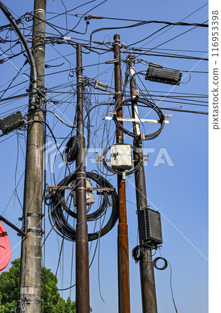 A bunch of power lines are tangled together and the sky is blue 116953398