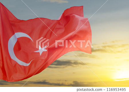 A Turkey flag with a star and crescent moon flying in the sky 116953495