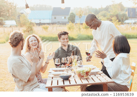 Friends having dinner in countryside, bonding over food, wine, laughter during getaway 116953639