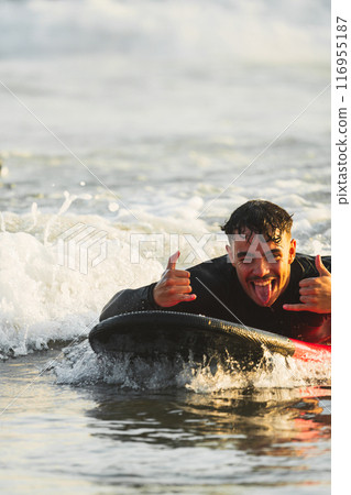 Brown-haired man enjoying surfing lessons for the first time 116955187