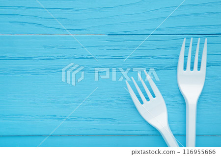 Two white plastic forks on a blue wooden background. Two white plastic forks on a blue wooden background. 116955666