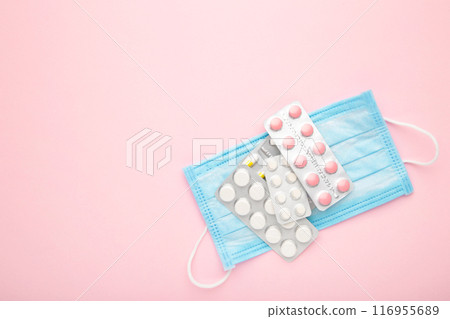 Medical face mask and pills on pink table background. Coronavirus COVID-19 concept. 116955689