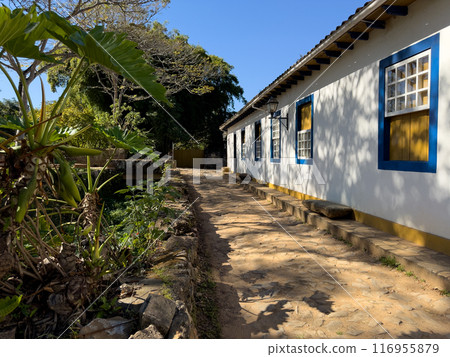 Traditional White House with Blue Windows in Serene Setting 116955879
