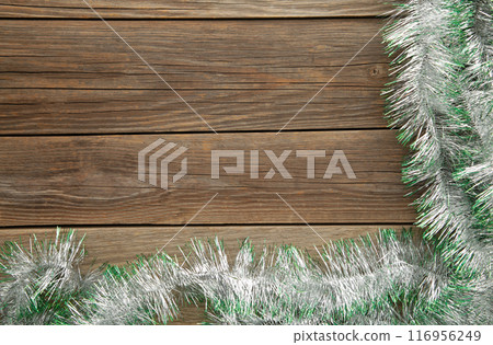 Christmas green and silver tinsel on grey wooden background. 116956249