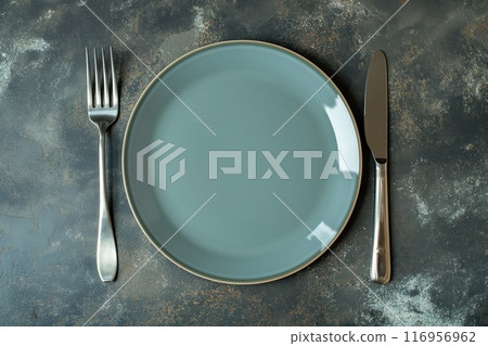Empty blue plate, knife and fork on dark background, top view 116956962