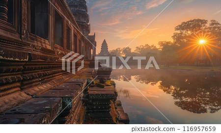 A serene sunrise bathes an ancient temple in golden light, illuminating carvings and casting a warm glow. 116957659