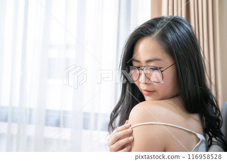 Asian Woman is posing with her sexy shoulder on her bed in the bedroom. 116958528