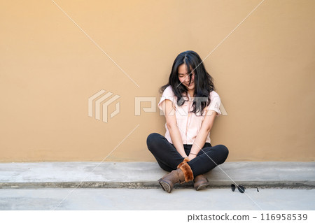 The Asian woman is sitting, crying and smiling alone at the same time on the rooftop of the building. This is not a good day for her. 116958539