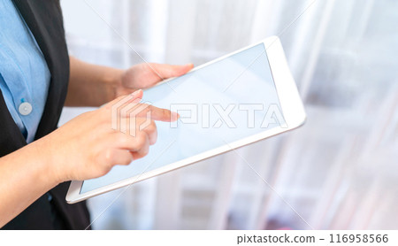 Close up to the White empty screen tablet which hold by Asina women in black suit in front of transparent curtain Close up to the White empty screen tablet which hold by Asina women in black suit in front of transparent curtain 116958566