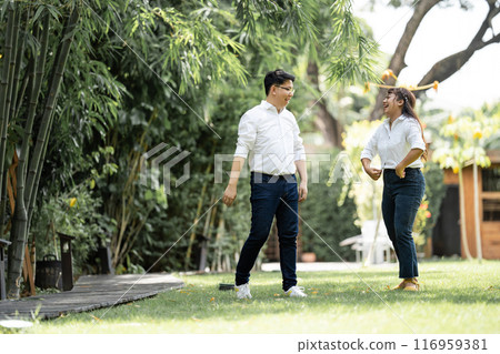 Asian Man and woman taking a pre wedding photo with woman grabbing his shoulder and bracing the man in the garden. Asian Man and woman taking a pre wedding photo with woman grabbing his shoulder and bracing the man in the garden. 116959381
