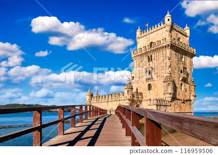 Belem tower and wooden bridge to it, Lisbon, Portugal at blue summer day sky with clouds. Medieval fort on Tagus river in late Gothic or Manueline style, UNESCO world heritage site, Age of Discoveries Belem tower and wooden bridge to it, Lisbon, Portugal at blue summer day sky with clouds. Medieval fort on Tagus river in late Gothic or Manueline style, UNESCO world heritage site, Age of Discoveries 116959506