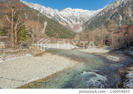 Azusa River and the Northern Alps in early winter as seen from Kamikochi in Nagano Prefecture. Snow falls on the mountaintops. The Northern Alps covered in snow. 116959955