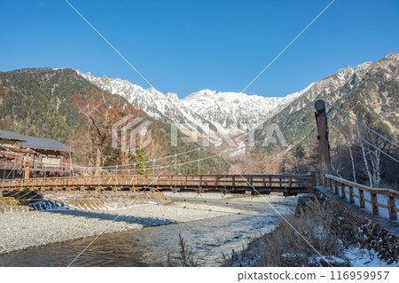 Azusa River and the Northern Alps in early winter as seen from Kamikochi in Nagano Prefecture. Snow falls on the mountaintops. The Northern Alps covered in snow. 116959957
