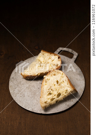 Two slices of homemade bread spread with butter. Still life in a rustic style Two slices of homemade bread spread with butter. Still life in a rustic style 116961072