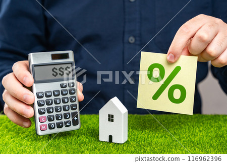 A man uses a calculator to calculate the cost of a house with a mortgage. Mortgage calculator. Study of real estate loan terms, risk assessment. Profitable proposition. 116962396