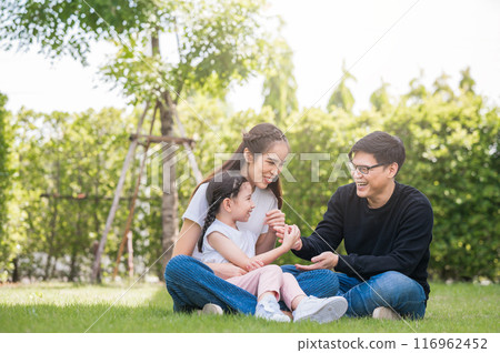 Happy Asian family mother, father and daughter having fun playing outside their home in garden 116962452