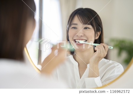 一位老婦一邊照鏡子一邊刷牙 116962572