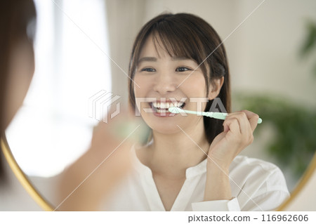 一位老婦一邊照鏡子一邊刷牙 一位老婦一邊照鏡子一邊刷牙 116962606