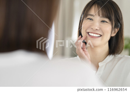 一個牙齒漂亮的女人看著鏡子微笑 一個牙齒漂亮的女人看著鏡子微笑 116962654