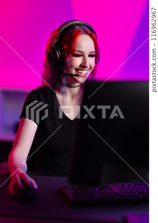 Professional gamer plays enthusiastically in a colorful room with headset and computer setup Professional gamer plays enthusiastically in a colorful room with headset and computer setup 116962967