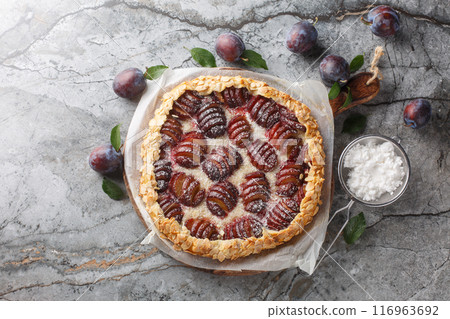 Freshly baked plum fruit pie with almonds close-up on a wooden board. Horizontal top view 116963692