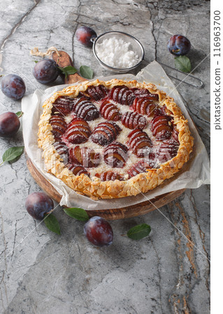 Delicious open pie plum galette with almonds close-up on a wooden board. Horizontal 116963700