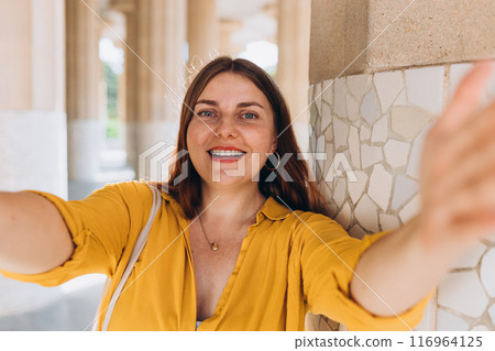 Beautiful female in Gaudi garden, Spain, Barcelona. Young traveling woman taking selfie outdoors. Concept of travel, tourism and vacation in city. Hypostyle hall Beautiful female in Gaudi garden, Spain, Barcelona. Young traveling woman taking selfie outdoors. Concept of travel, tourism and vacation in city. Hypostyle hall 116964125