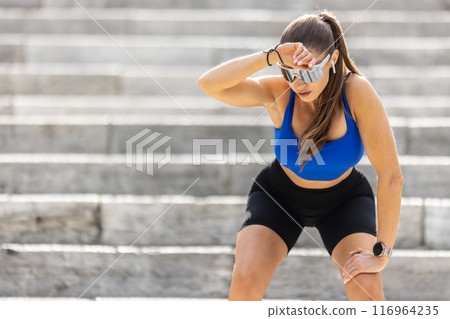 A tired young female runner rests after an exhausting run up the stairs A tired young female runner rests after an exhausting run up the stairs 116964235