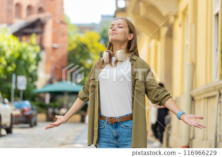 Caucasian young woman taking a deep breath of fresh air, relaxing and meditating on city street 116966229