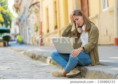 Displeased young woman using laptop working, loses becoming surprised sudden lottery result outdoors 116966233