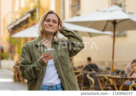 Woman using smartphone texting social media messages looking for a way on navigator map city street Woman using smartphone texting social media messages looking for a way on navigator map city street 116966247