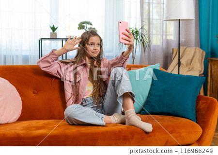 Happy child girl blogger taking selfie on smartphone communicating video call with subscribers Happy child girl blogger taking selfie on smartphone communicating video call with subscribers 116966249